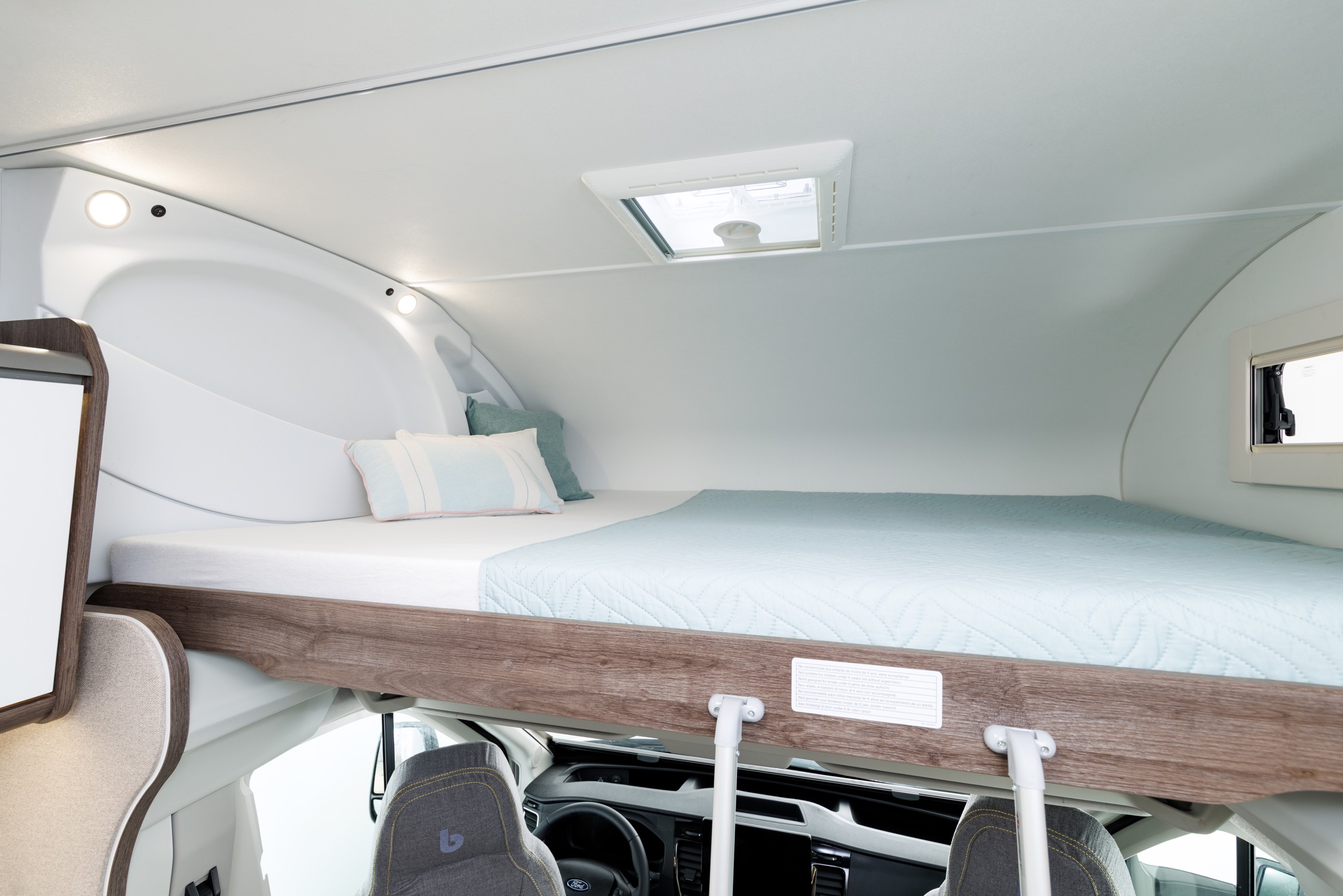 Cama capuchina sobre la cabina con ropa de cama y claraboya